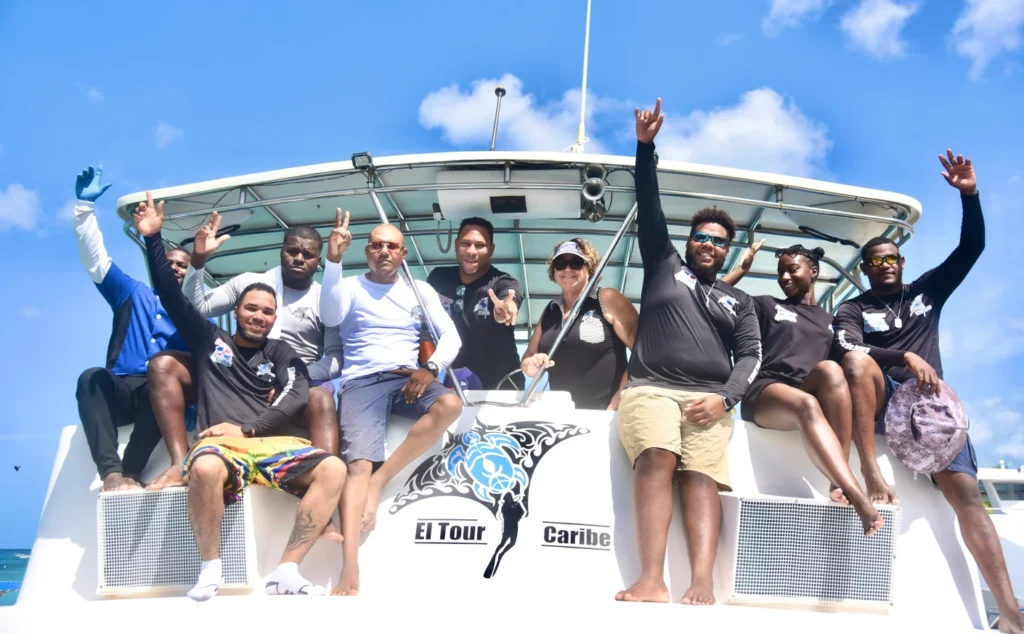 El Tour Caribe crew aboard and beside La Dichosa in turquoise Caribbean water.
